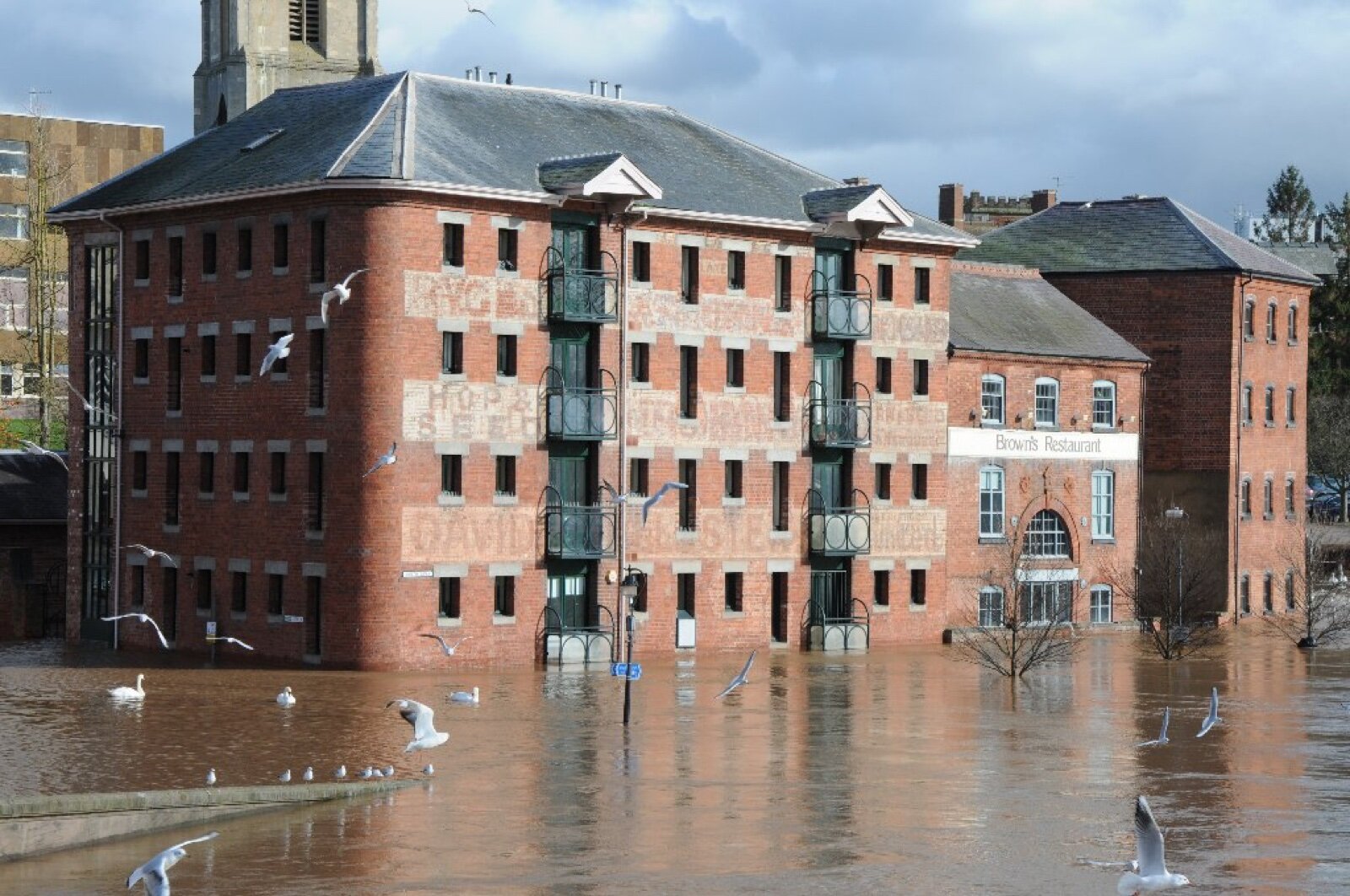 Converted riverside warehouse buildings standing in flood water