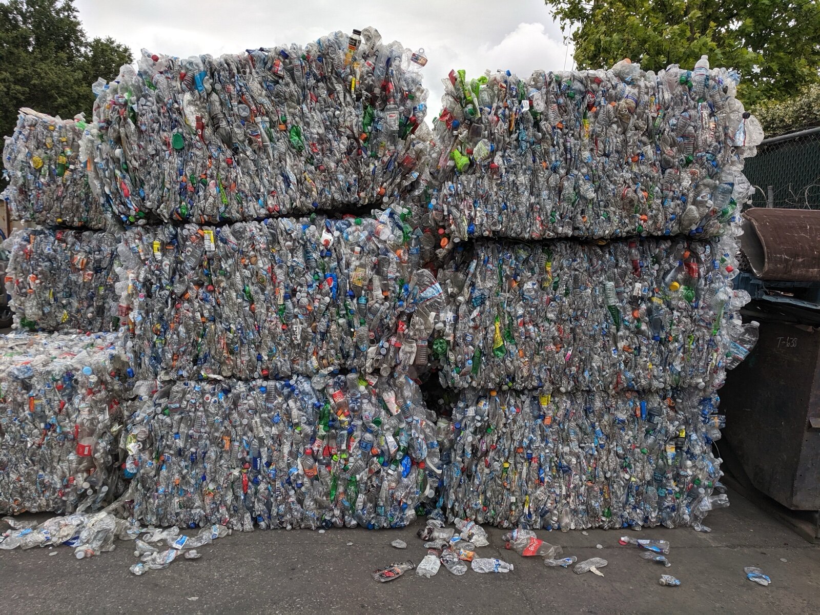 Large stacked bales of crushed plastic drinks bottles in a recycling yard