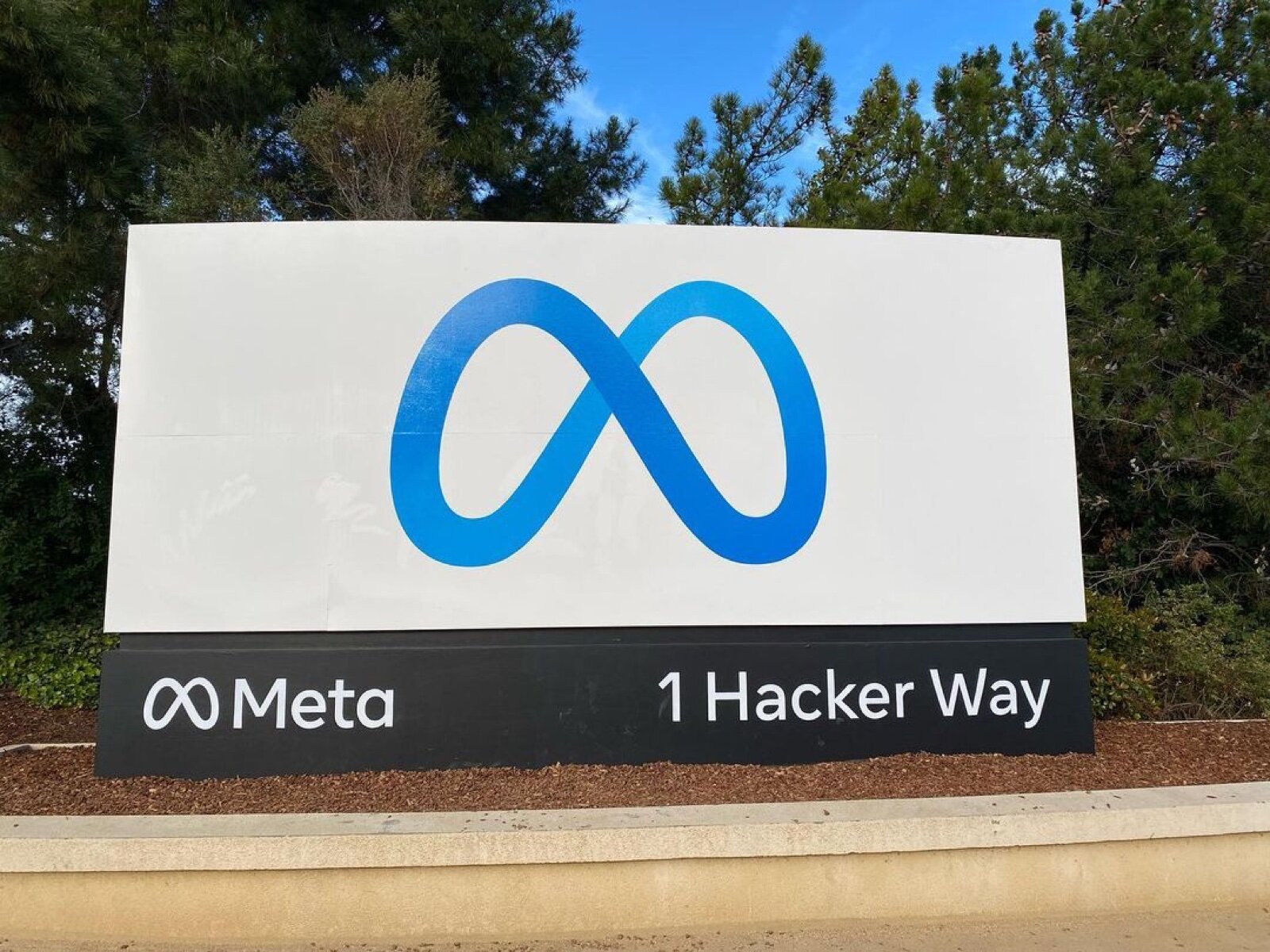 Meta entrance sign with the infinity logo and 1 Hacker Way at its headquarters in Menlo Park, California